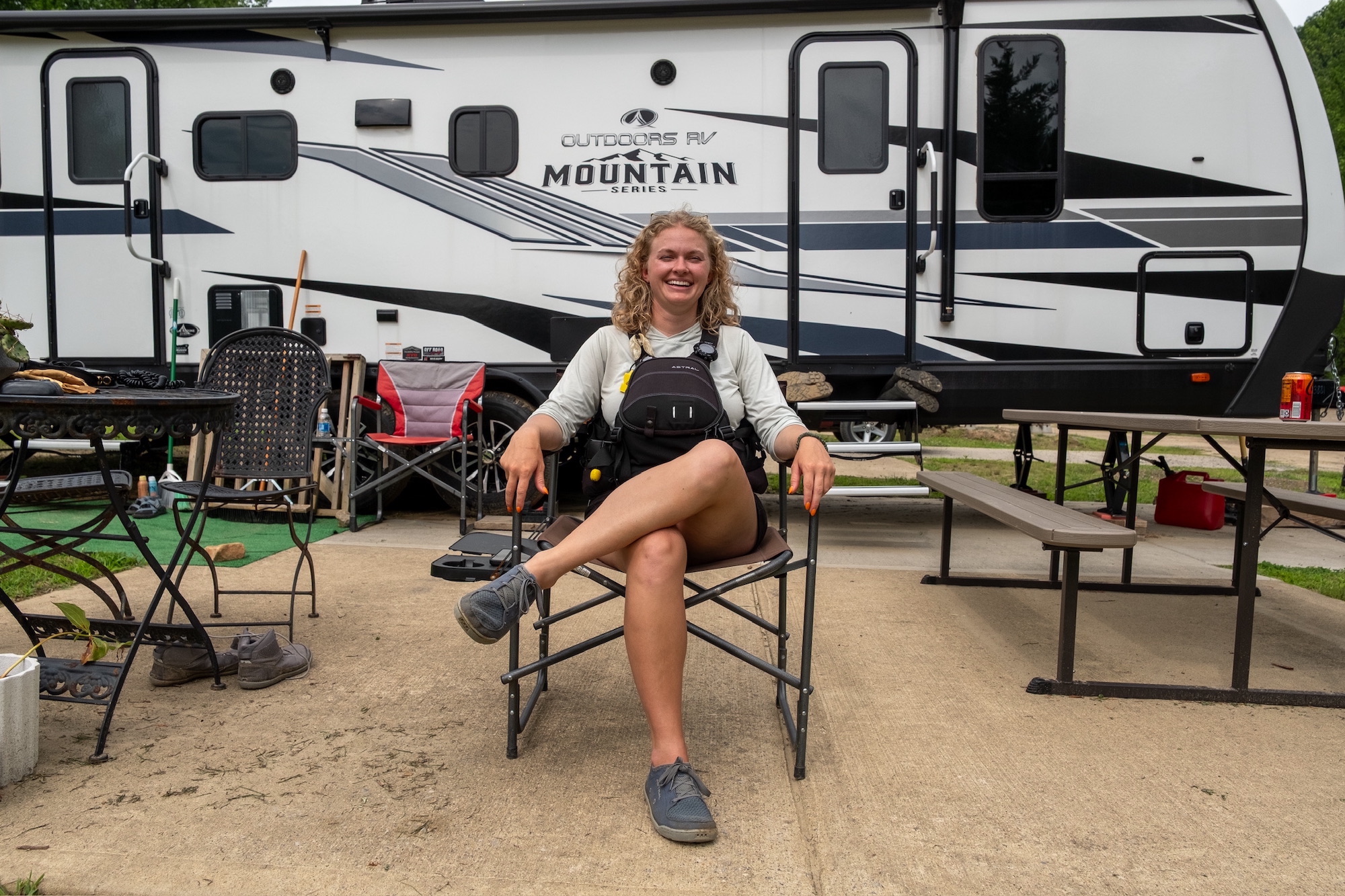 A young woman sits in a camp chair outside a trailer