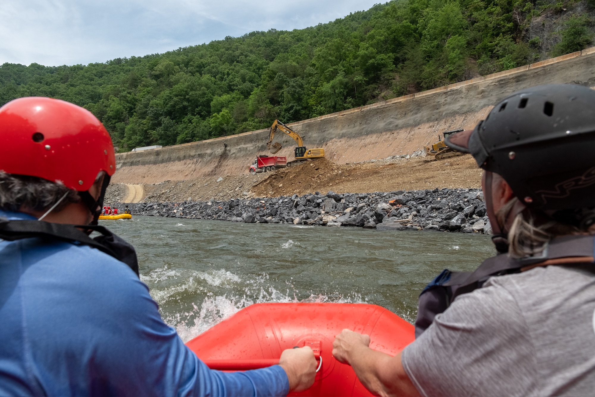 two rafters look at a construction site near the edge of the water